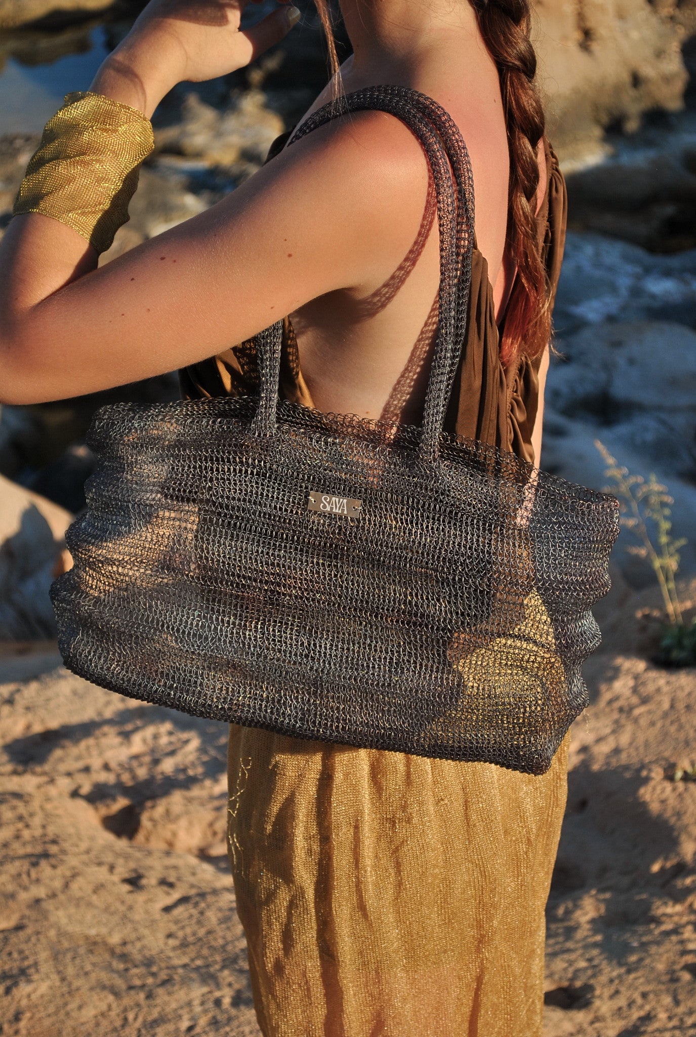 Bolso Ombak negro artesanal de SAYA llevado por una modelo en una cala.