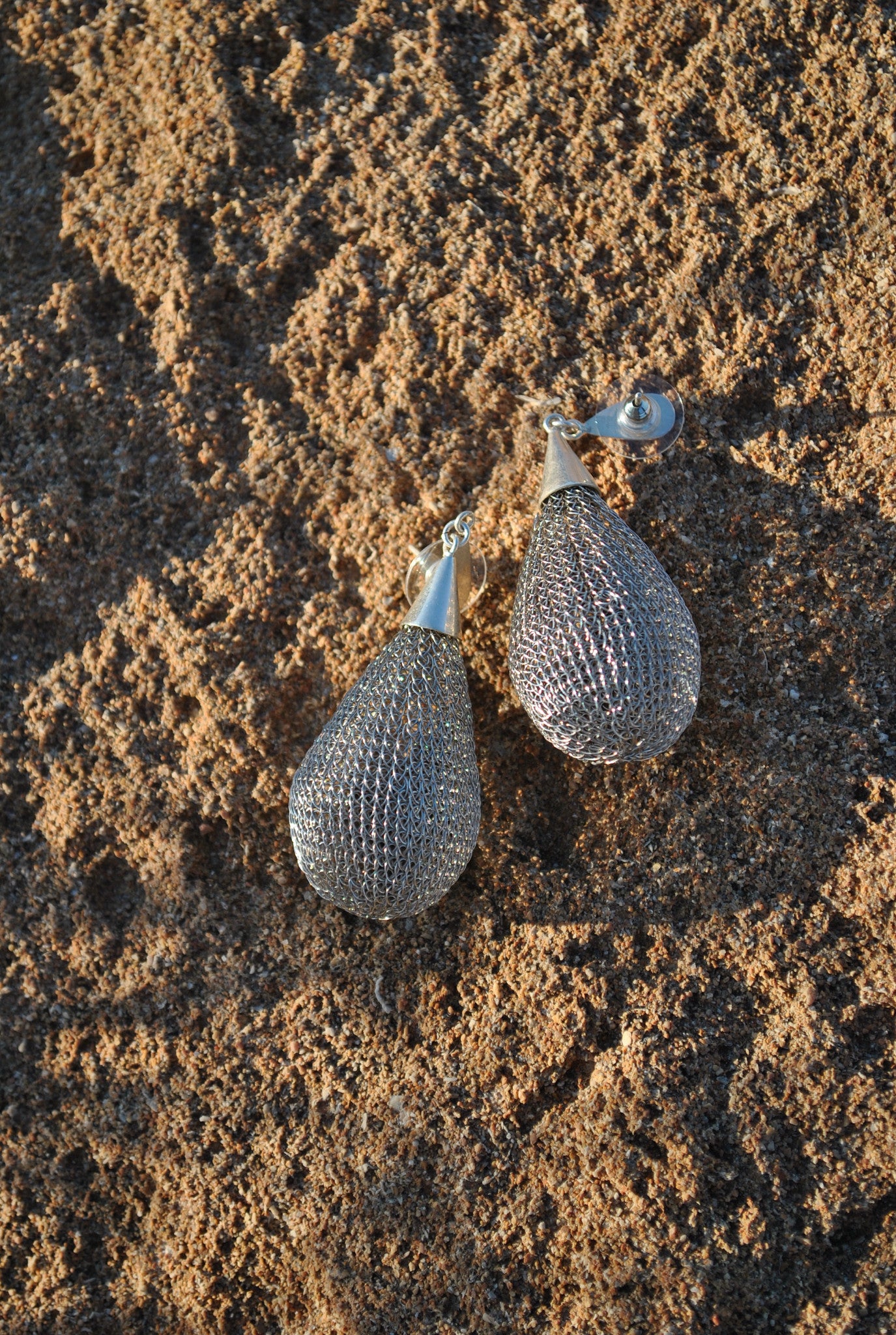 Pendientes Glop Plata de SAYA sobre roca junto al mar, tejidos a mano en crochet metálico
