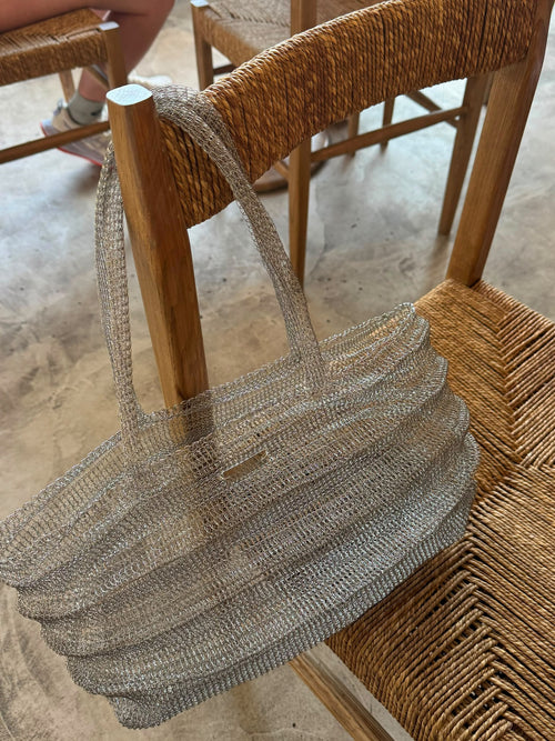 Bolso Ombak plata tejido a mano en crochet metálico en una silla
